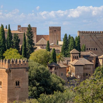 A majestic view of Alhambra in Granada, showcasing its medieval Islamic architecture and lush gardens.